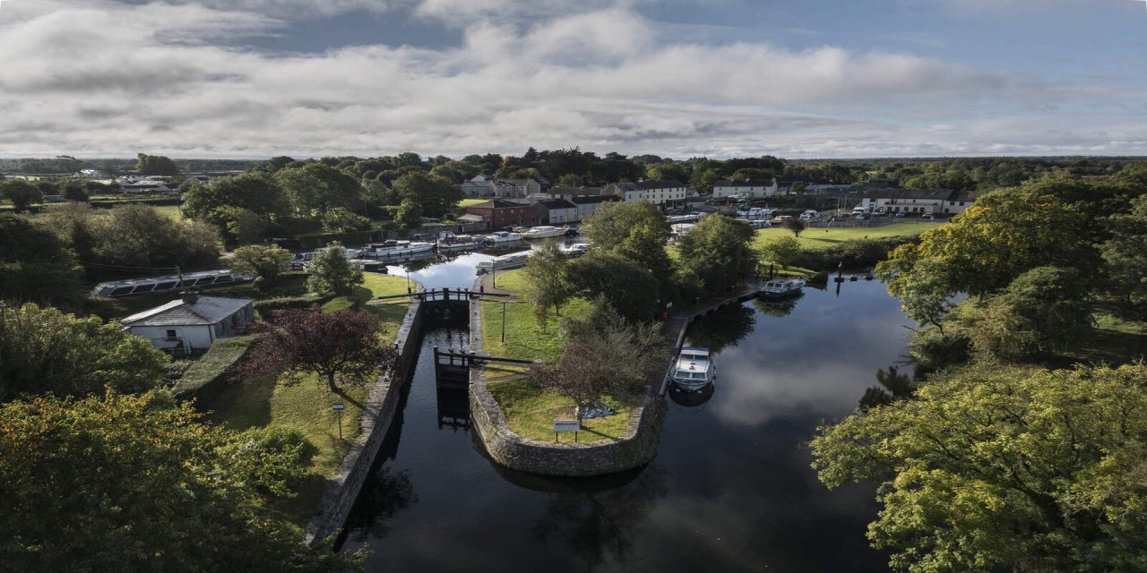 Blue skies with white clouds, tall green trees and forests beside the blue river